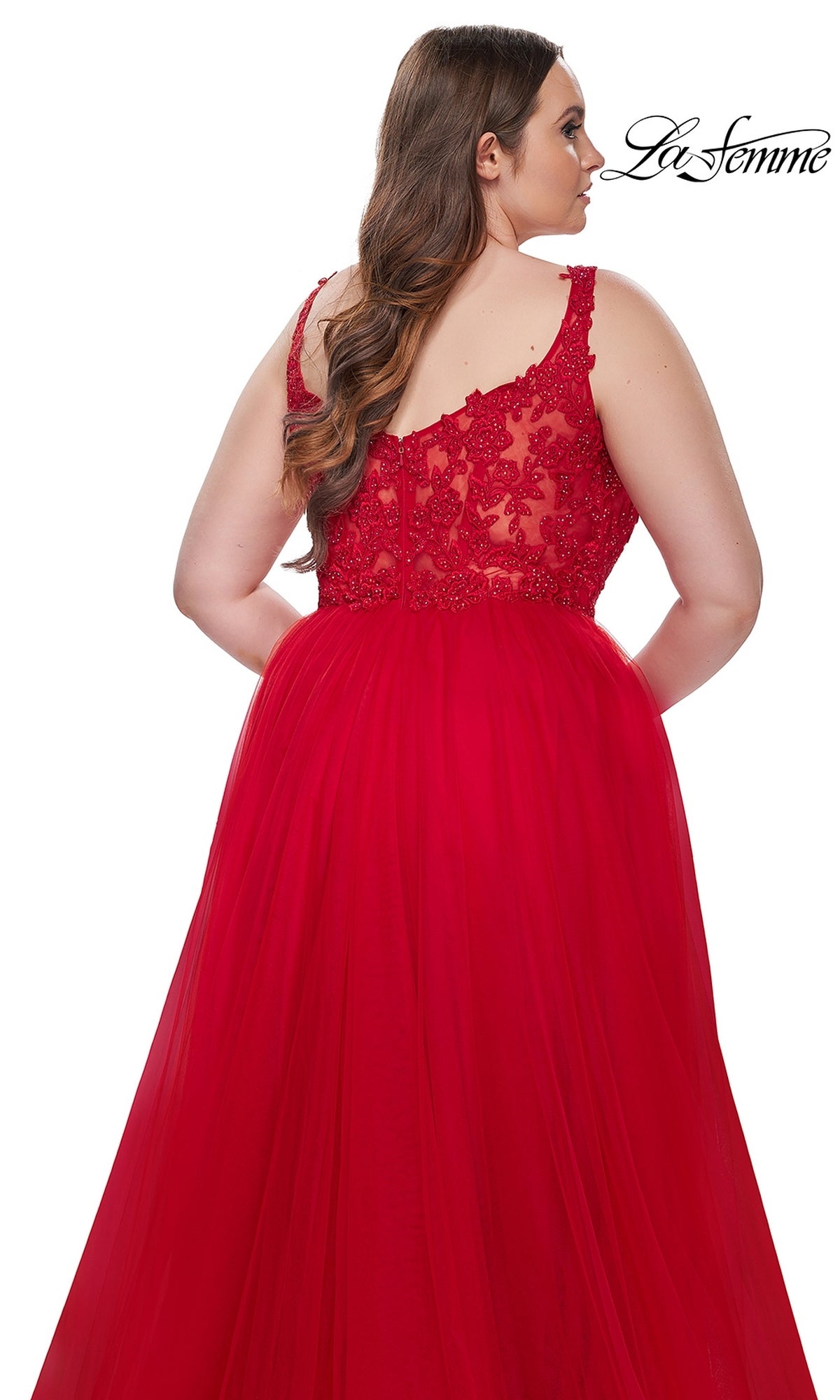 A woman with long brown hair wears the La Femme Long Prom Dress 31394—a red, sleeveless gown with an embroidered lace bodice back—standing against a white background. The La Femme logo is in the top right corner.